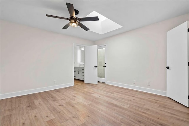 unfurnished bedroom featuring a skylight, baseboards, ensuite bath, and light wood finished floors