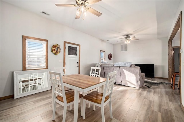 dining space with ceiling fan and light wood-type flooring