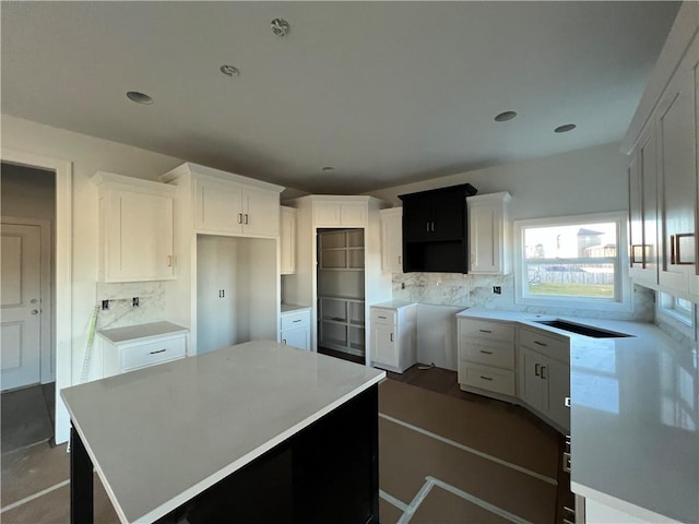 kitchen with tasteful backsplash, white cabinetry, and a center island