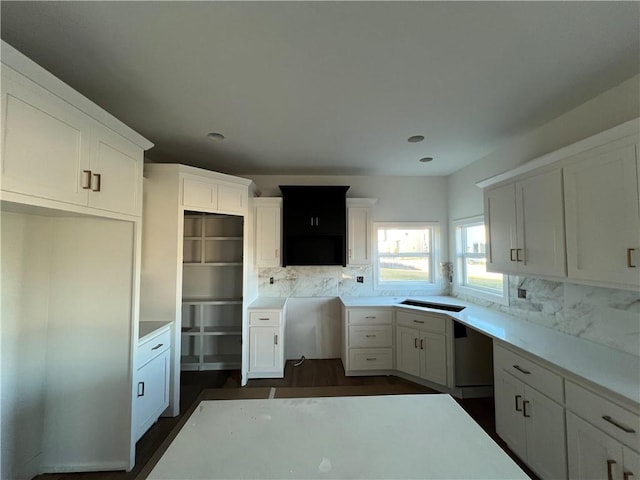 kitchen featuring dark hardwood / wood-style floors, built in desk, decorative backsplash, and white cabinets