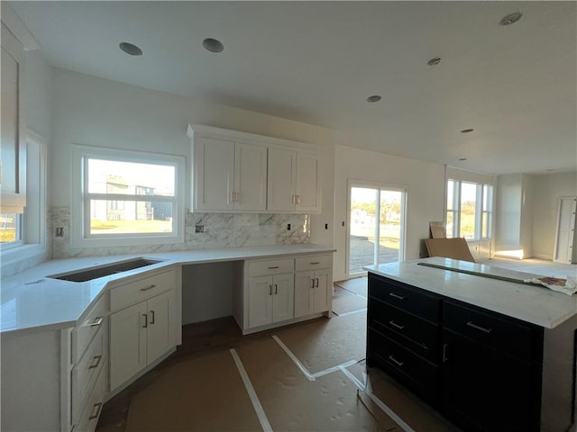 kitchen with white cabinetry, a center island, sink, and decorative backsplash