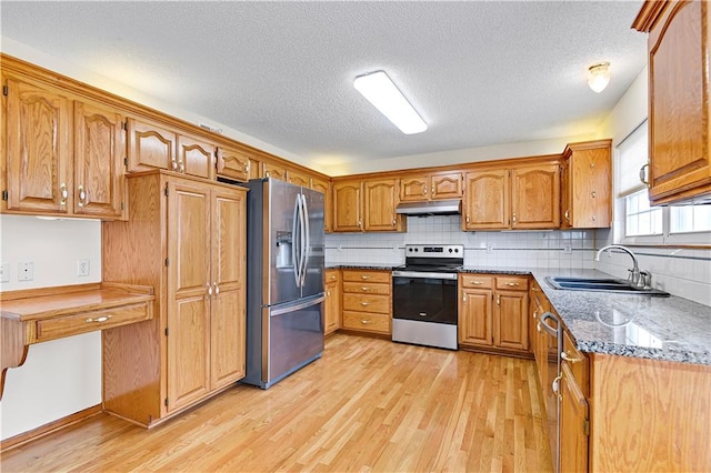 kitchen featuring sink, light hardwood / wood-style flooring, appliances with stainless steel finishes, backsplash, and light stone countertops