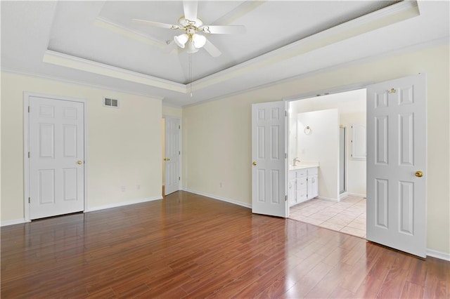 spare room with crown molding, wood-type flooring, a raised ceiling, and ceiling fan