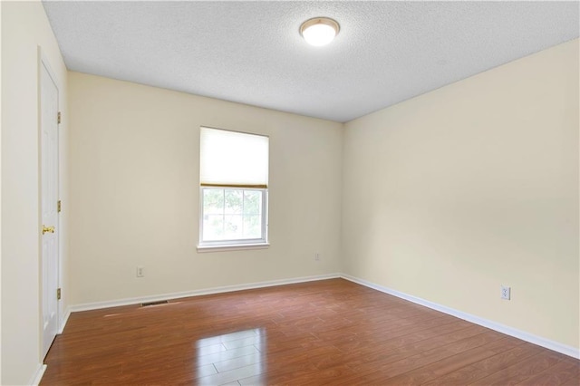 unfurnished room featuring hardwood / wood-style flooring and a textured ceiling