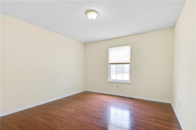 unfurnished room featuring dark wood-type flooring and a textured ceiling