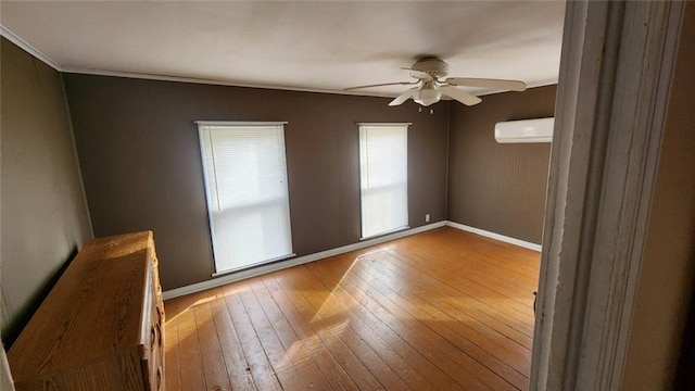 unfurnished room featuring an AC wall unit, hardwood / wood-style floors, and ceiling fan