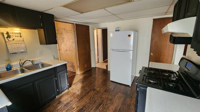 kitchen with sink, dark hardwood / wood-style flooring, gas range oven, a drop ceiling, and white fridge