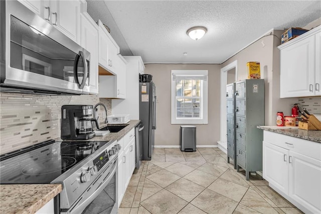 kitchen with sink, a textured ceiling, appliances with stainless steel finishes, white cabinets, and backsplash