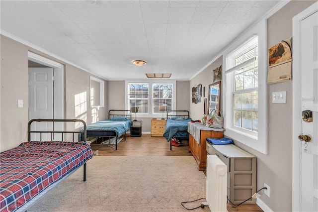 bedroom with multiple windows, ornamental molding, and light hardwood / wood-style flooring