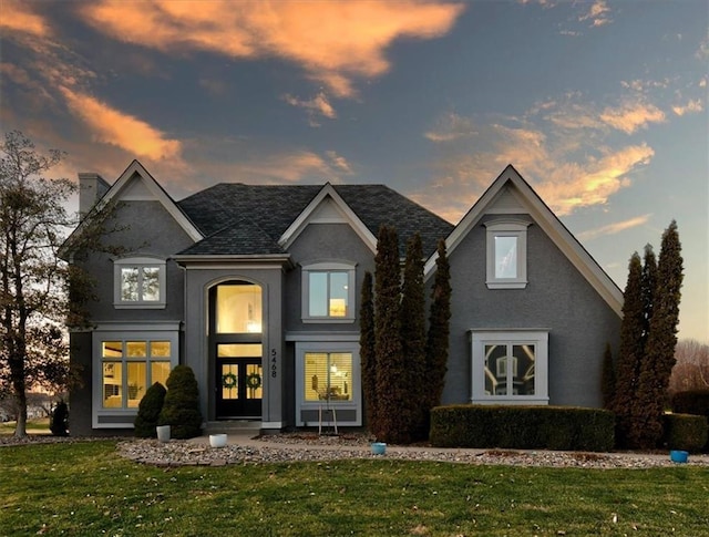 view of front of property with stucco siding, french doors, a chimney, and a front yard