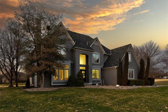 traditional home featuring stucco siding and a yard