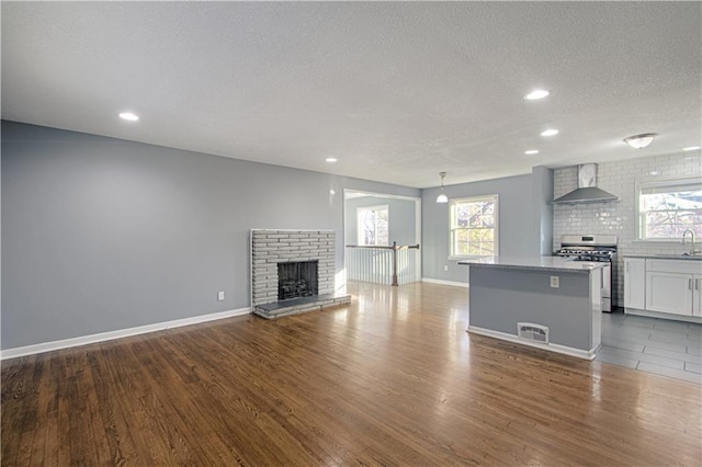 unfurnished living room featuring sink, hardwood / wood-style flooring, a fireplace, and a textured ceiling