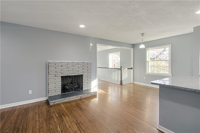 unfurnished living room featuring a textured ceiling, a fireplace, and wood-type flooring