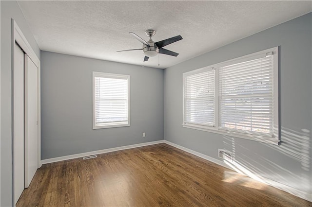 unfurnished bedroom featuring dark wood-type flooring, ceiling fan, a closet, and a textured ceiling