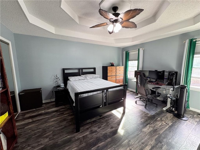 bedroom featuring a tray ceiling, dark wood-type flooring, and a textured ceiling