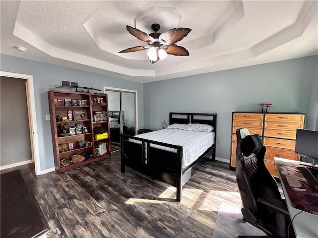 bedroom featuring a closet, dark hardwood / wood-style floors, a raised ceiling, and a textured ceiling