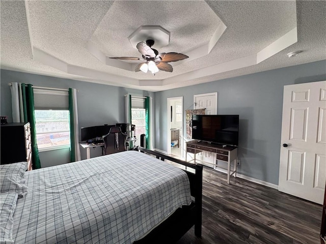 bedroom featuring dark wood-type flooring, a tray ceiling, and a textured ceiling