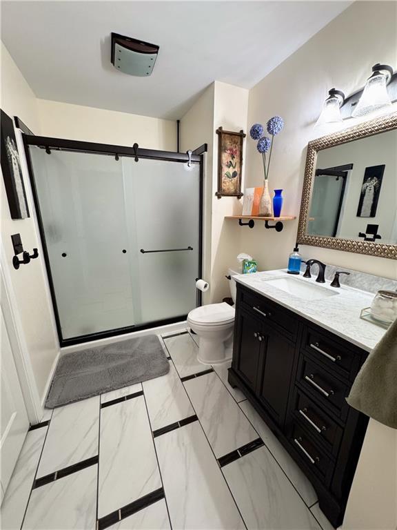 bathroom featuring walk in shower, vanity, and toilet