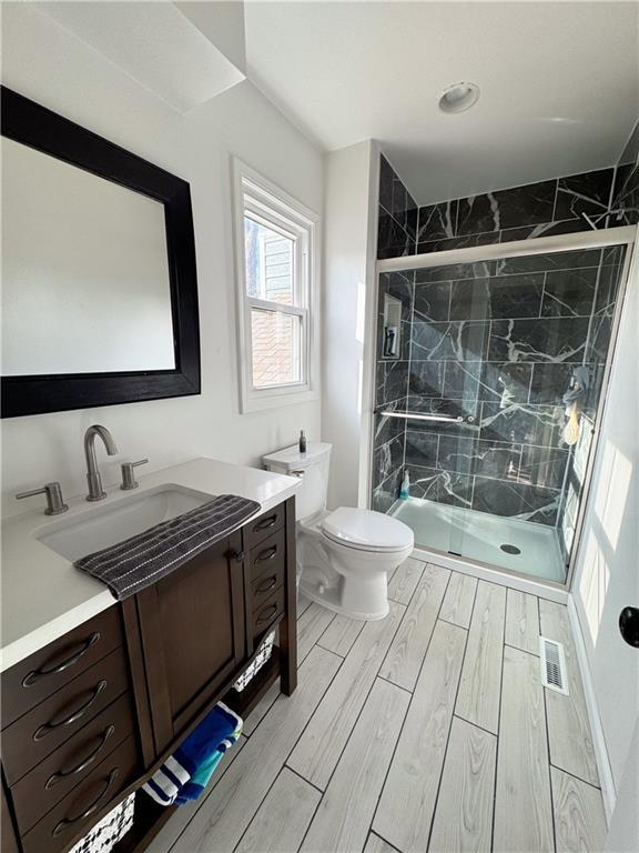 bathroom with walk in shower, vanity, and toilet