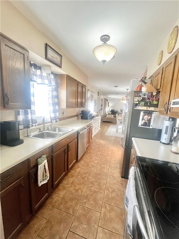 kitchen with sink, a wealth of natural light, stainless steel appliances, and light tile patterned flooring