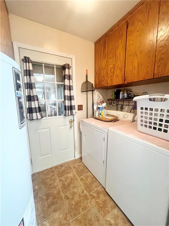 clothes washing area with cabinets and washer and clothes dryer