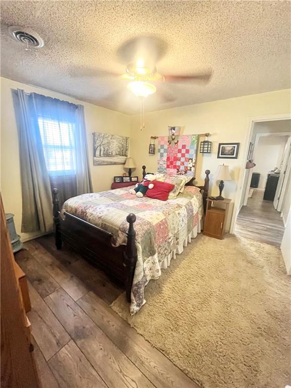 bedroom featuring hardwood / wood-style floors, a textured ceiling, and ceiling fan