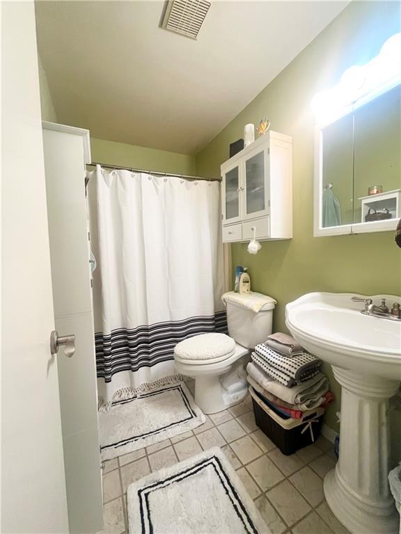 bathroom with a shower with shower curtain, toilet, and tile patterned flooring