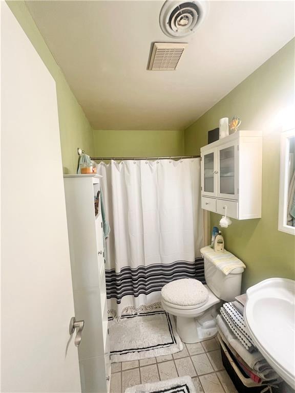 bathroom featuring tile patterned flooring, sink, curtained shower, and toilet