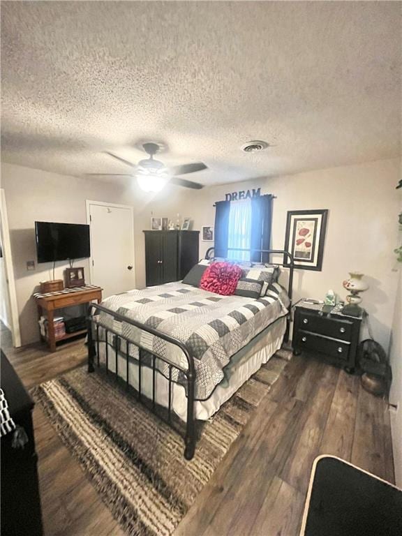 bedroom with dark wood-type flooring, a textured ceiling, and ceiling fan