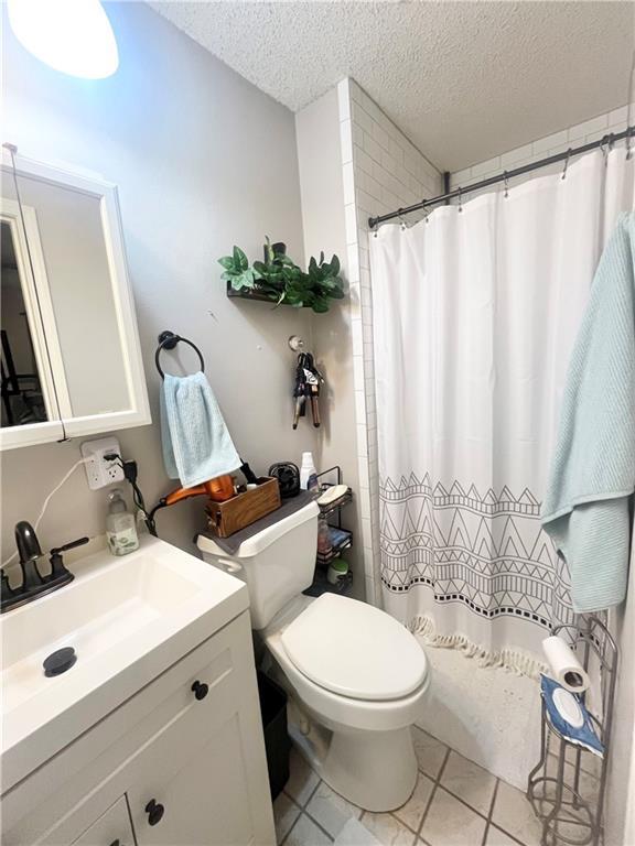 bathroom featuring vanity, curtained shower, a textured ceiling, and toilet