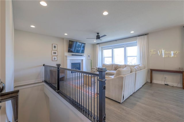 living area with a tiled fireplace, recessed lighting, light wood-style floors, and a ceiling fan
