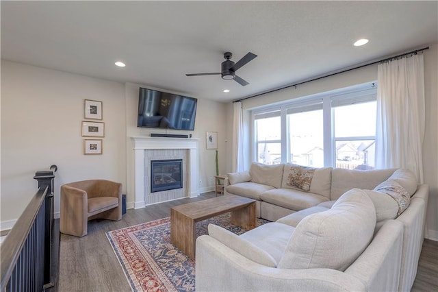 living area with a ceiling fan, recessed lighting, a tile fireplace, and wood finished floors
