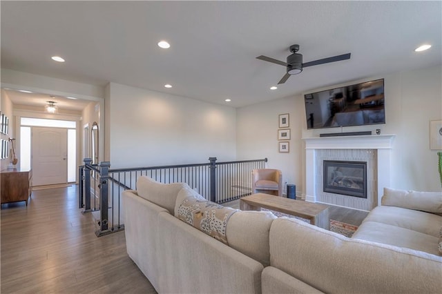 living room with a tiled fireplace, wood finished floors, ceiling fan, and recessed lighting