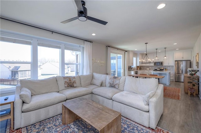 living room featuring wood finished floors, recessed lighting, and ceiling fan with notable chandelier