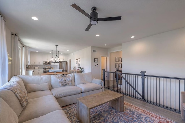 living area featuring visible vents, wood finished floors, recessed lighting, and ceiling fan with notable chandelier
