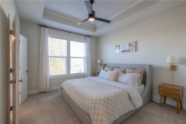carpeted bedroom with a ceiling fan, a raised ceiling, and baseboards