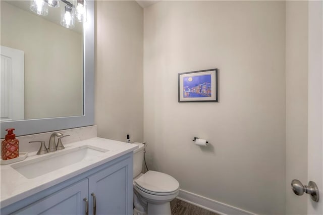 half bath featuring toilet, vanity, and baseboards