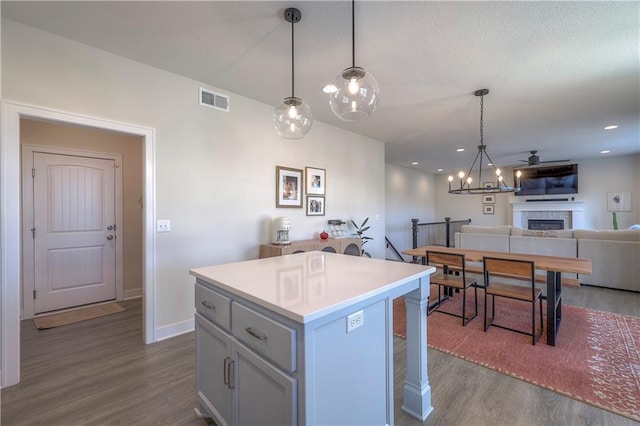 kitchen with dark wood finished floors, a kitchen island, visible vents, and a fireplace
