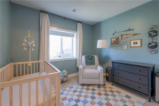 carpeted bedroom featuring baseboards, visible vents, and a nursery area