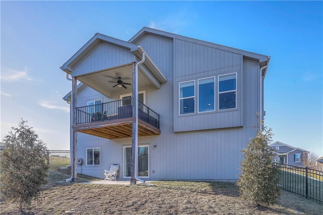 back of property with a balcony, fence, a ceiling fan, and a patio area