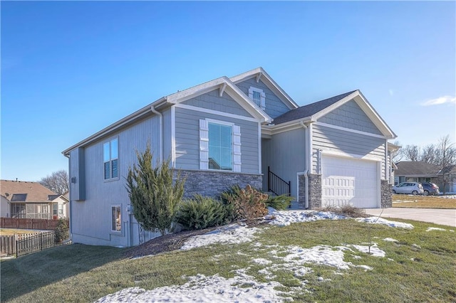 view of front of house featuring stone siding, concrete driveway, fence, a front lawn, and a garage