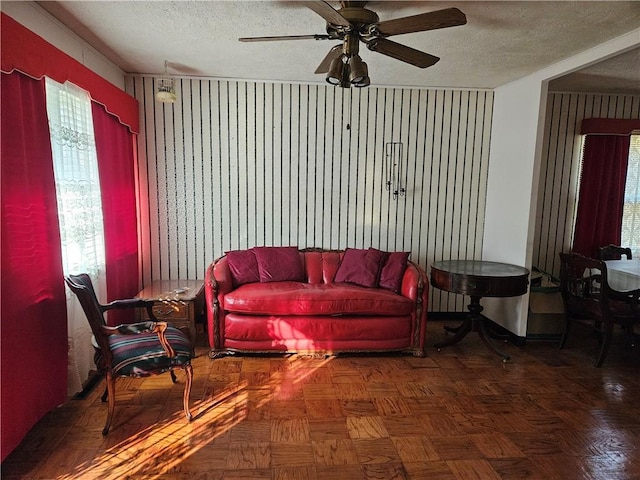 living room with ceiling fan, dark parquet flooring, and a textured ceiling