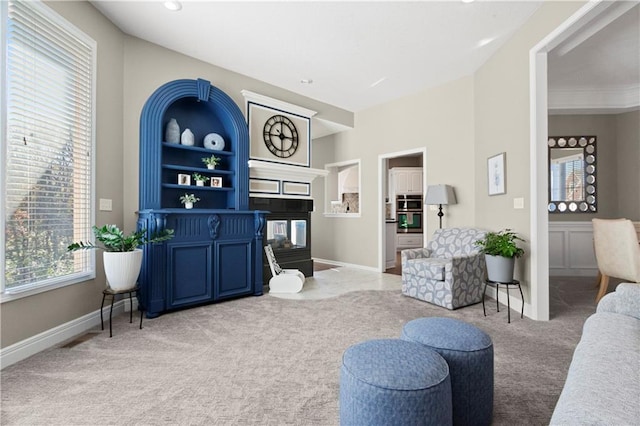 carpeted living room featuring a multi sided fireplace and baseboards