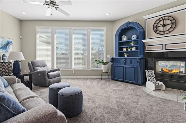 living room with recessed lighting, a ceiling fan, light carpet, a tile fireplace, and baseboards