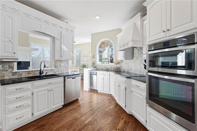 kitchen featuring custom exhaust hood, white cabinetry, appliances with stainless steel finishes, and a sink