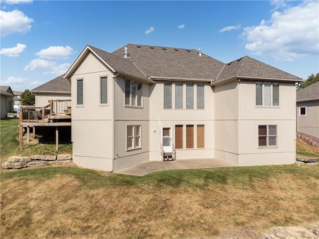 rear view of property with a yard, a deck, and a patio