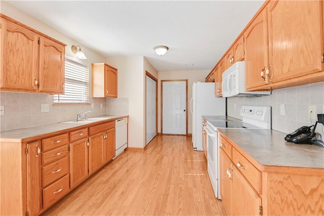 kitchen featuring tasteful backsplash, sink, white appliances, and light hardwood / wood-style flooring