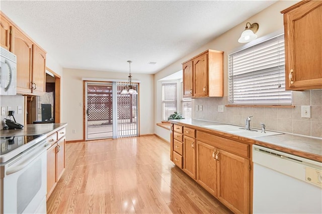 kitchen featuring decorative backsplash, white appliances, sink, and hanging light fixtures