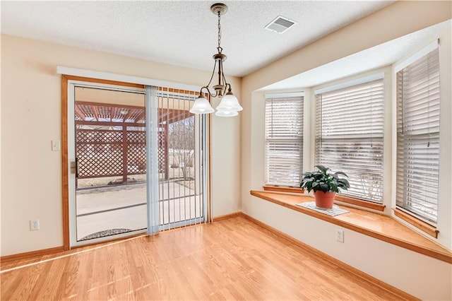 unfurnished dining area with wood-type flooring and a textured ceiling