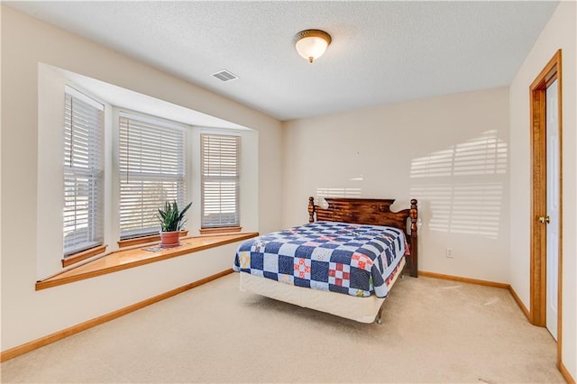 bedroom with multiple windows, carpet floors, and a textured ceiling